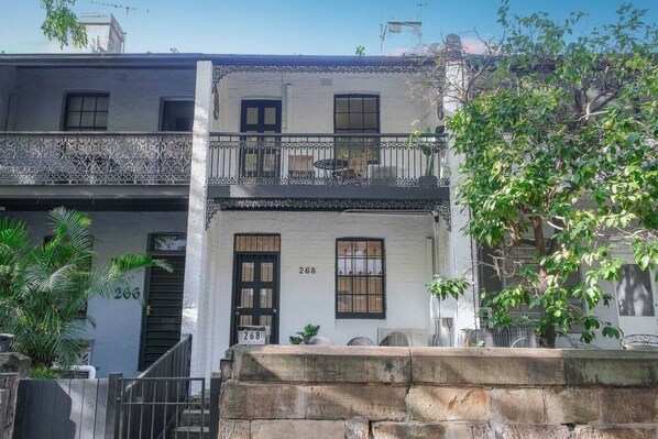 A two-story building with a balcony, numbered 268, and a stone wall in the foreground.