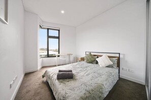Una camera da letto con un letto, una finestra, un tavolino e una sedia.