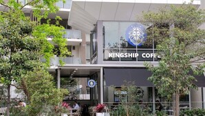 A Kingship Coffee building with a modern design, outdoor seating, and a visible logo. - Spacious Mascot 2BR Near Airport + Parking/Pets (Mascot)