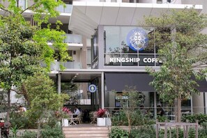 Ein Gebäude von Kingship Coffee mit modernem Design, Außenplätzen und einem sichtbaren Logo.