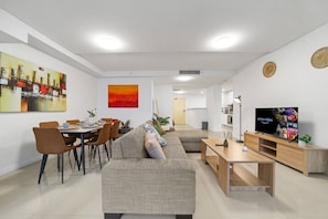Ein modernes Wohnzimmer mit Sofa, Esstisch und Fernseher.