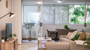 A modern living room with a sofa, TV, and dining area. - Spacious Mascot 2BR Near Airport + Parking/Pets (Mascot)