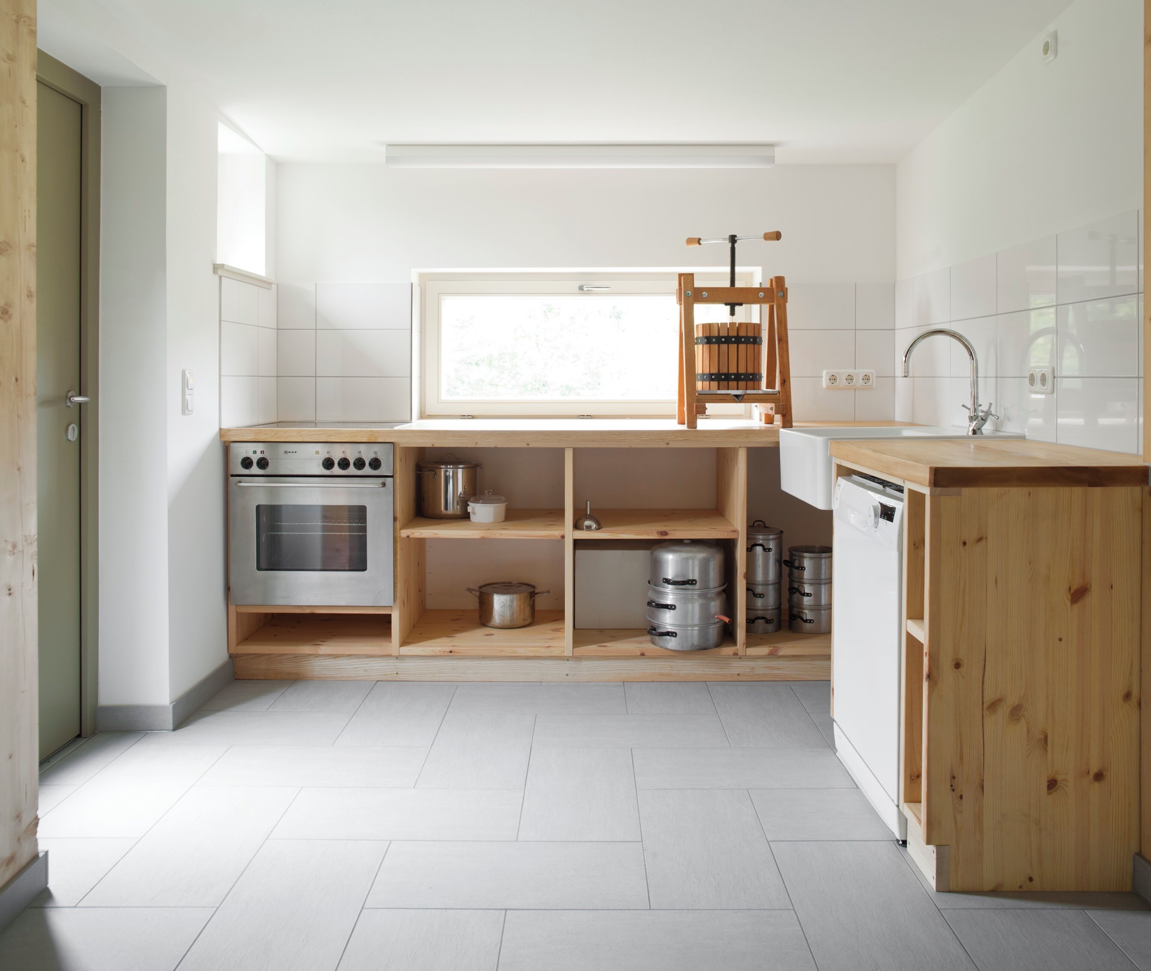 Una cocina compacta con horno integrado, repisas de madera, una ventana y un lavamanos.