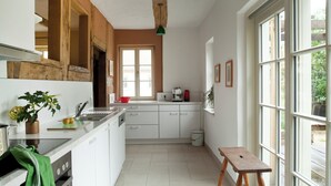 A kitchen with white cabinets, a wooden ceiling, and a large window.