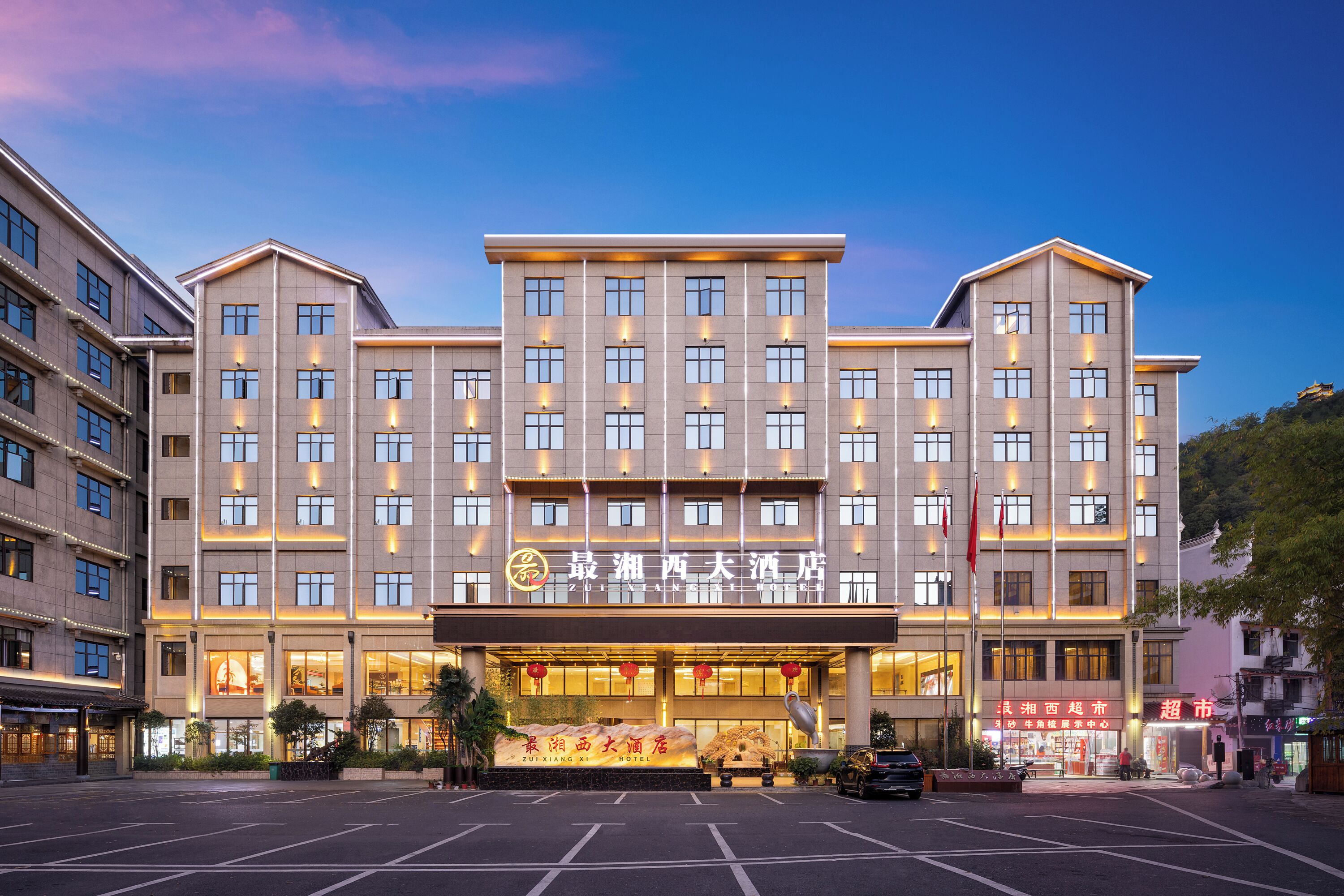 A multi-story hotel with a prominent entrance, large windows, and a well-lit facade.