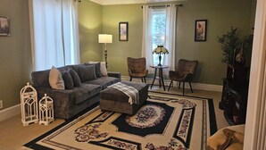 Ein Wohnzimmer mit einer Couch, zwei Sesseln, einem Couchtisch, einem gemusterten Teppich und einer Lampe.