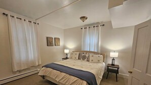 Ein Schlafzimmer mit einem Bett, zwei Nachttischen, einem Heizgerät und einer Tür.