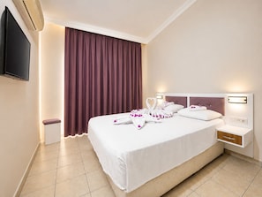 A hotel room with a bed, a TV, a bedside table, and a wall-mounted light. - SAYGILI BEACH HOTEL (Manavgat)