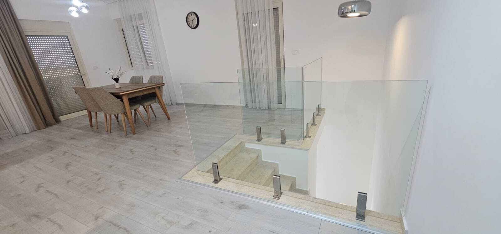 Un intérieur moderne comprenant un coin repas, un escalier et une rambarde en verre.