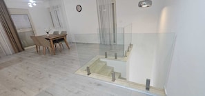 Ein modernes Interieur mit Essbereich, Treppe und Glasgeländer.