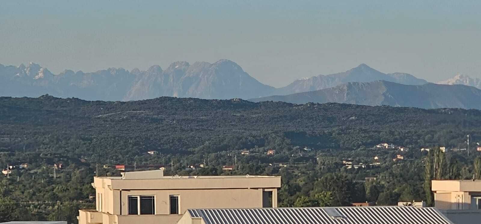 A mountainous landscape with buildings in the foreground.
