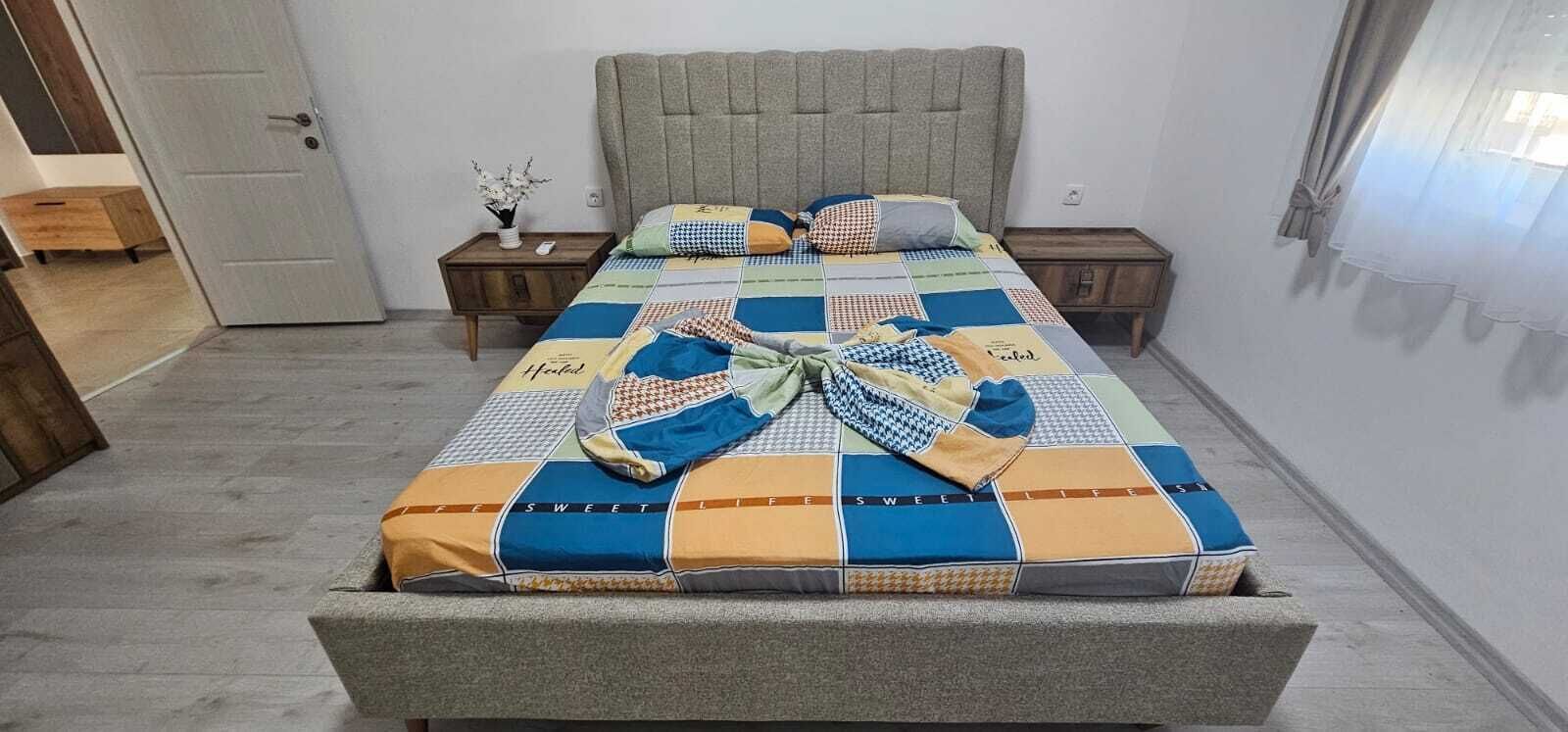 A bed with a quilt, a bedside table with a vase, and a nightstand with a phone.