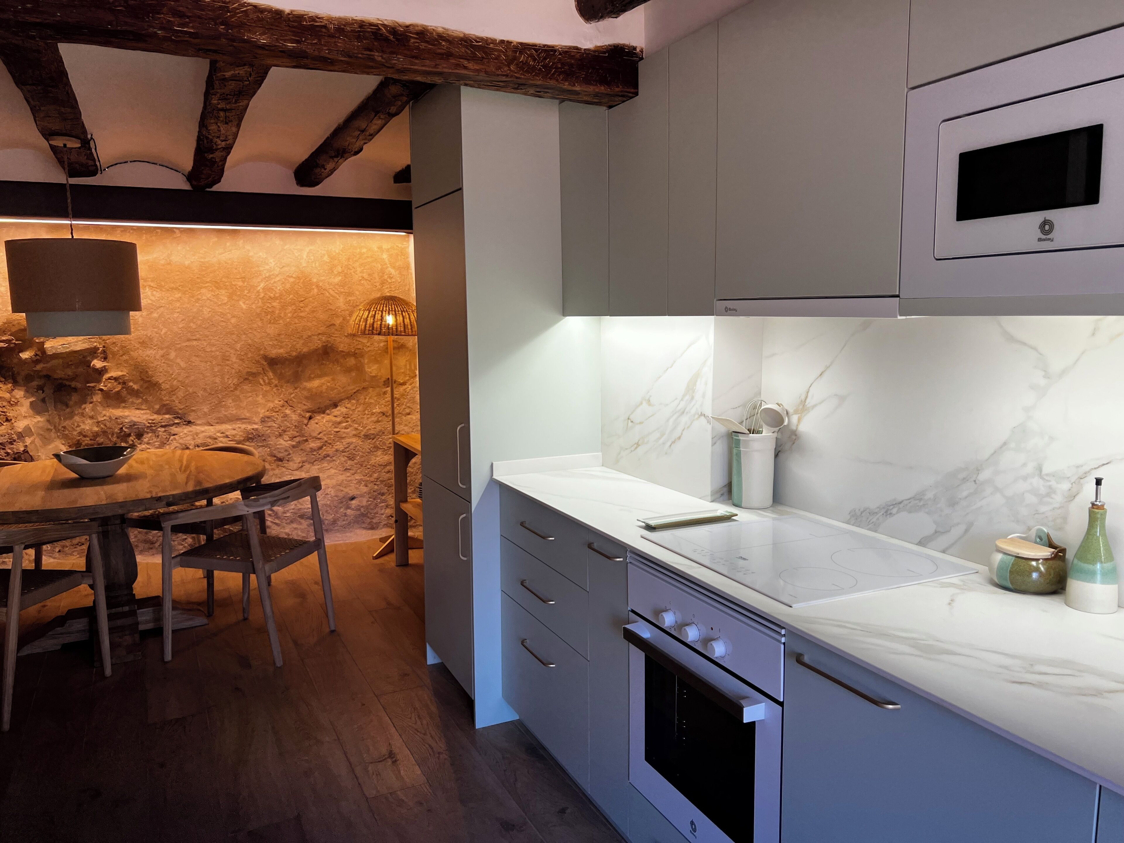Una cucina con parete in pietra, travi in legno, un piano di lavoro in marmo e forno a incasso.