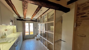 Une cuisine dotée d’un plan de travail en marbre, de poutres en bois et d’une porte-fenêtre coulissante donnant sur un balcon.