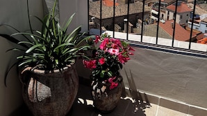 Un balcon agrémenté de plantes en pot, offrant une vue sur la ville et les montagnes.