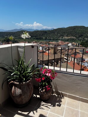 Un balcon agrémenté de plantes en pot, offrant une vue sur la ville et les montagnes.
