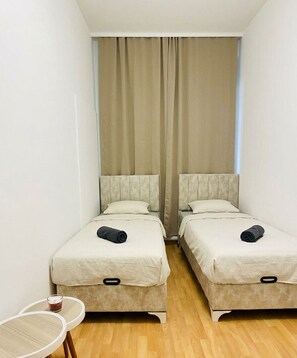 A small hotel room with two beds, a small table, and a window with curtains. - Affordable Room in a Calm Neighborhood (Wien)