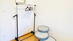 A room with a metal rack holding clothes, a small table, and a framed picture on the wall. - Affordable Room in a Calm Neighborhood (Wien)