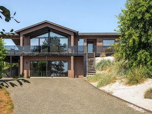 A modern two-story house with a prominent balcony, large windows, and a gravel driveway. - 5 Star Holiday Home in Ebeltoft (Ebeltoft)