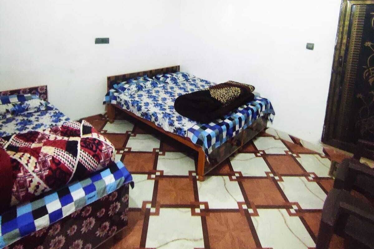A room with two beds, a ceiling fan, and a patterned floor.