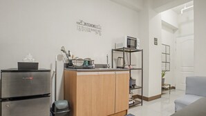 Una cocina compacta con refrigerador, microondas y armarios de madera.