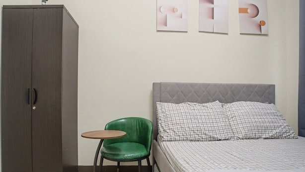 Un dormitorio con una cama, una silla verde, una mesita y un armario.