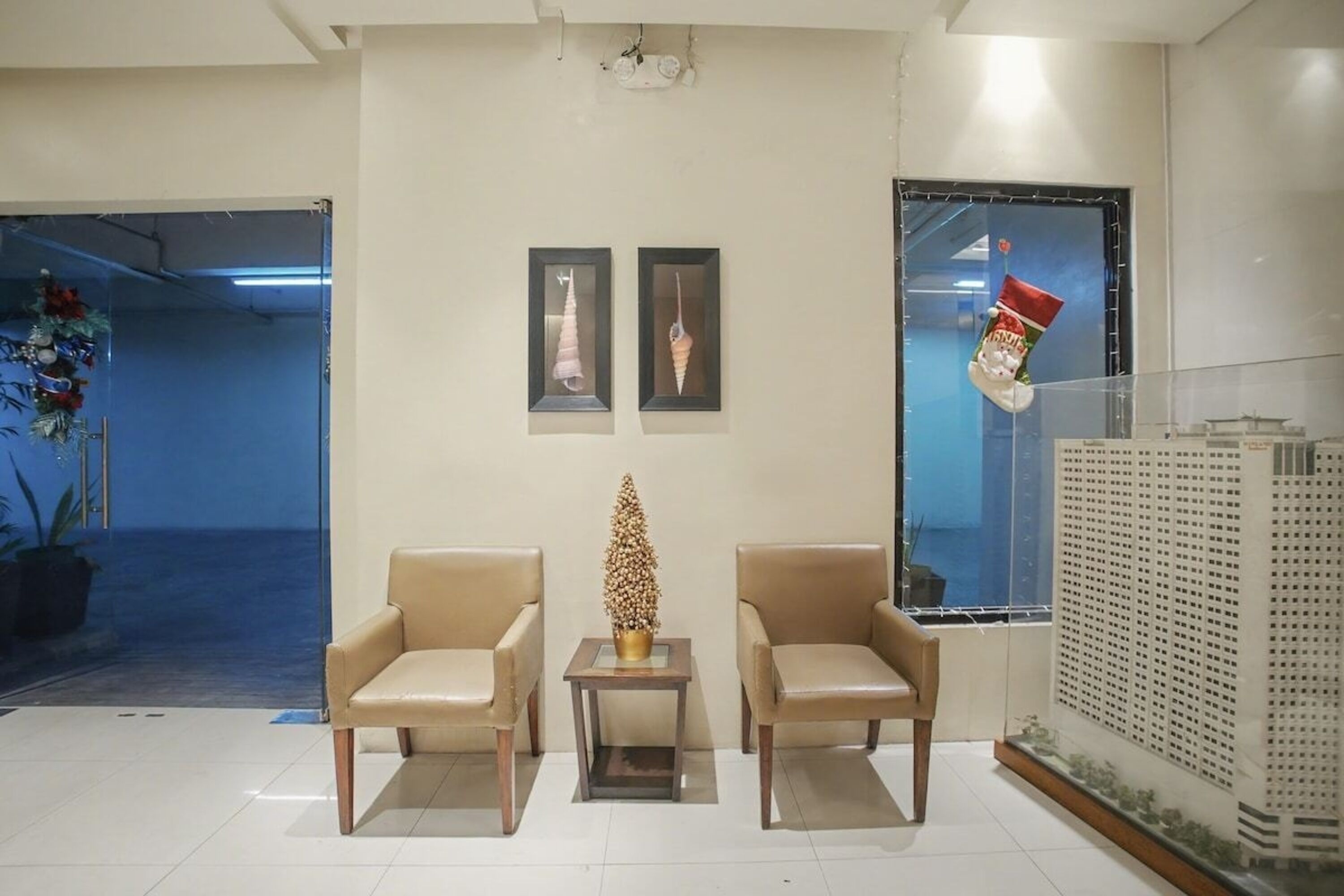 A lobby with two leather chairs, a small table with a decorative item, framed pictures on the wall, and a Christmas stocking on the window sill.