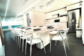 Eine moderne Küche mit einer zentralen Kochinsel, weißen Stühlen und einem Edelstahlkühlschrank.