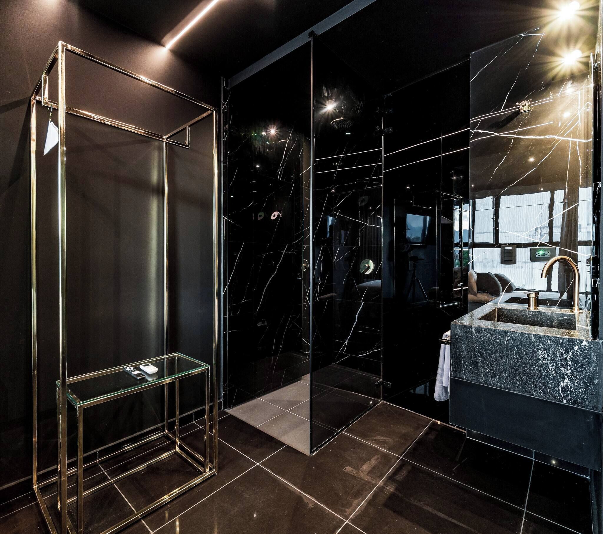 Un baño moderno con cabina de ducha de vidrio, un lavamanos con encimera de mármol y un espejo grande que refleja el ambiente.