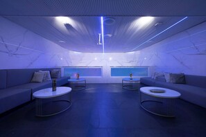 Eine moderne Lounge mit Marmorwänden, zwei Sofas und runden Tischen.
