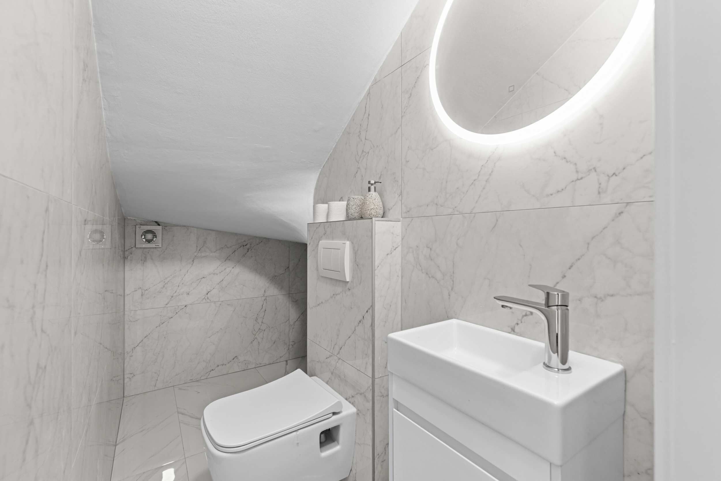 A modern bathroom with a toilet, sink, and a wall-mounted mirror.