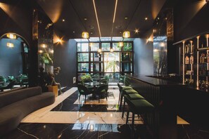 A modern bar area with a marble floor, green seating, and a large window providing a view of the outdoors. - Aman Luxury 23 Bedroom 3 Pool (Medellín)