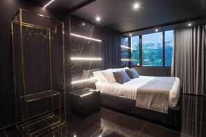 A modern hotel room with a large bed, a glass display unit, and a view of the cityscape through the window. - Aman Luxury 23 Bedroom 3 Pool (Medellín)