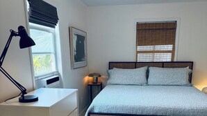 A bedroom with a bed, a nightstand, a desk, a ceiling fan, and a window with blinds. - The Pink Beach House in Delray Beach for a perfect getaway (Delray Beach)