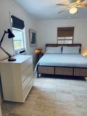 A bedroom with a bed, a nightstand, a desk, a ceiling fan, and a window with blinds. - The Pink Beach House in Delray Beach for a perfect getaway (Delray Beach)