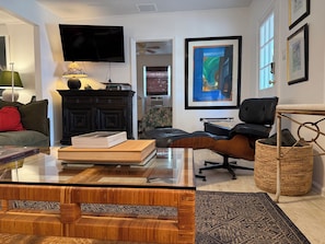 A modern living room with a glass coffee table, a black leather sofa, a black armchair, a black cabinet, and a large framed abstract painting. - The Pink Beach House in Delray Beach for a perfect getaway (Delray Beach)