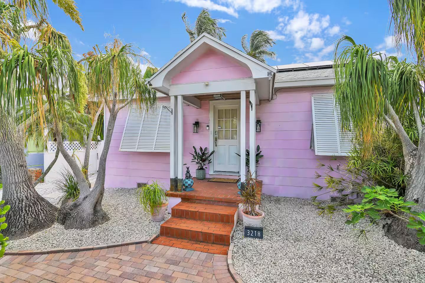 A pink house with a front porch, steps, and a mailbox marked 3218.