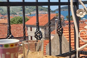 Ein Balkon mit Blick auf Häuser mit roten Dächern und ein Gewässer.