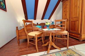 Ein Zimmer mit einem hölzernen Bett, einem runden Holztisch mit Stühlen, einem Holzschrank und einer blauen Decke.
