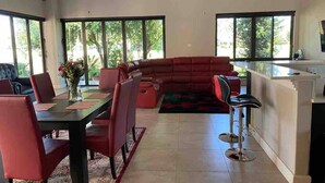Una sala de estar moderna con comedor, ventanas amplias y una cocina.
