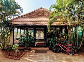 A building with a tiled roof, a front entrance with a door, and a bicycle parked outside. - THE HERITAGE RESORT (Badami)