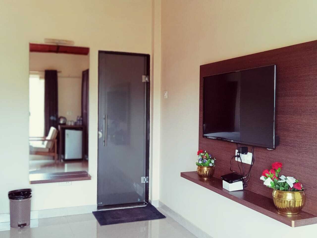 A modern interior with a sliding glass door, a mounted flat-screen TV, and two decorative vases on a wooden shelf.