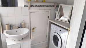 Un bagno compatto con lavandino, WC e lavatrice.