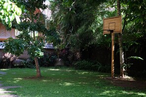 A basketball court with a wooden backboard, surrounded by lush greenery and trees. - Cacao House Eco-Luxe Family home near Green School (Kecamatan Abiansemal)