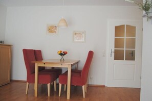 Ein Essbereich mit einem Holztisch, roten Stühlen, einer Pendelleuchte und zwei gerahmten Bildern an der Wand.