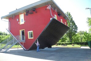 Ein rotes Gebäude mit einem schiefen Dach, einer Treppe und einer Person in der Nähe des schiefen Teils.