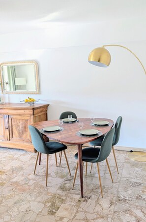 A dining area with a wooden table, six chairs, and a gold floor lamp. - 3 rooms with parking 700 meters from the sea (Cagnes-sur-Mer)