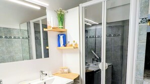 Ein modernes Badezimmer mit einem großen Waschbecken, einem Spiegel und einem Duschbereich.
