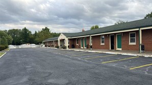 A row of motel rooms with a parking lot in front. - King Bed|Smoking|Aurora (Aurora, IN)