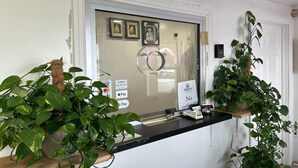 A reception area with a glass door, a counter with a cash register, and two potted plants. - King Bed|Smoking|Aurora (Aurora, IN)